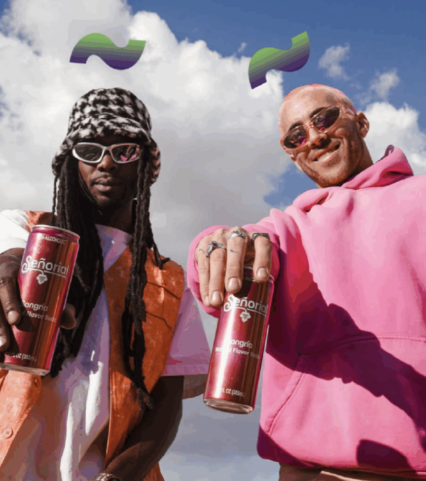 Two stylish friends holding cans of Señorial Sangría soda outdoors, posing confidently against a bright sky with playful graphic accents above them.