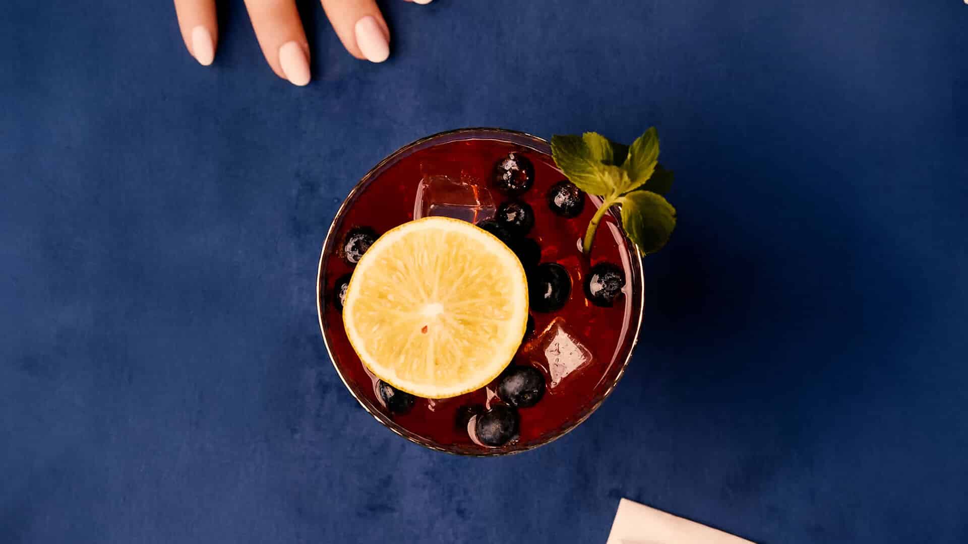 Top view of a Sangria Senorial mocktail with citrus slice, fresh berries, and mint, styled as a refined and refreshing non-alcoholic drink.