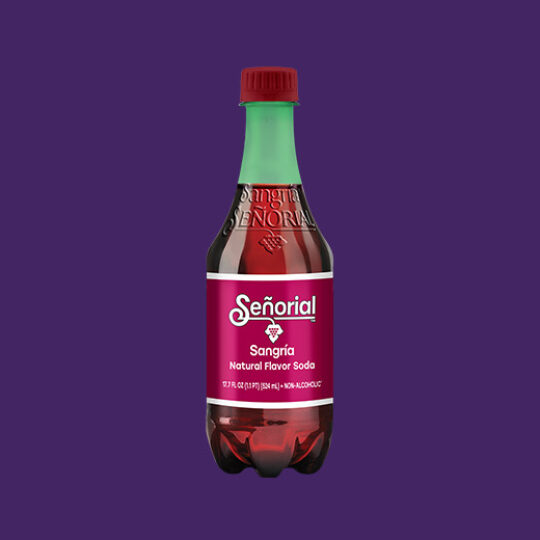 Single bottle of Sangría Señorial natural flavor soda centered on a solid purple background, showcasing its signature burgundy label and green cap.
