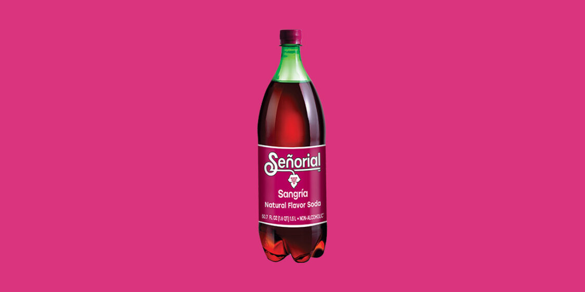 Bottle of Sangría Señorial natural flavor soda displayed at the center of a bright pink background, showcasing its deep red color and iconic label.