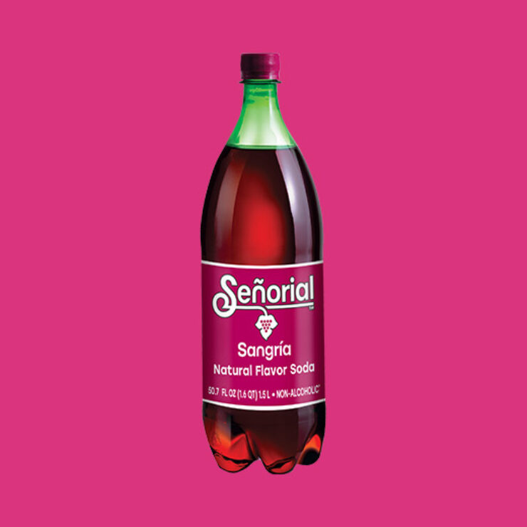Bottle of Sangría Señorial natural flavor soda displayed at the center of a bright pink background, showcasing its deep red color and iconic label.