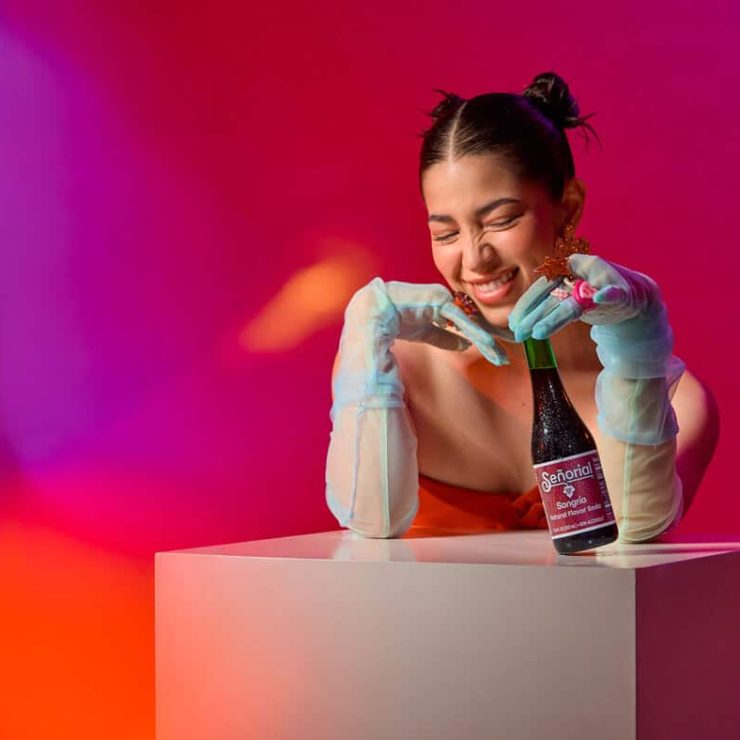 Playful lifestyle portrait with a Sangria Senorial bottle, showcasing vibrant color, joyful expression, and a modern premium non-alcoholic vibe.